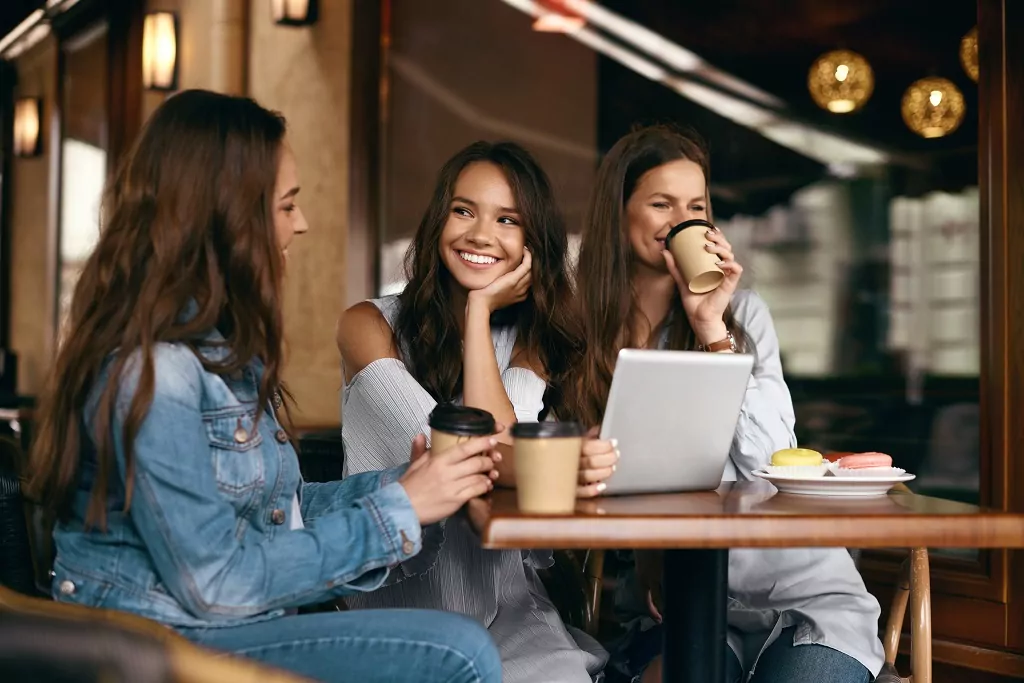 Beautiful smiling girls using tablet at a coffee shop.