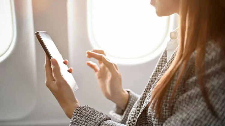businesswoman using smartphone to read messages during flight