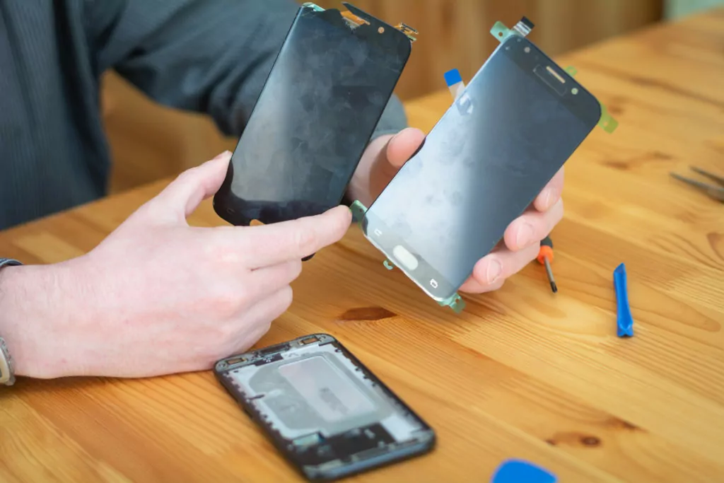 A technician is replacing the broken screen on a smartphone.