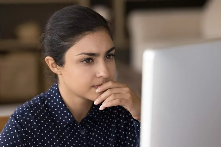 Pensive female professional working at computer from home
