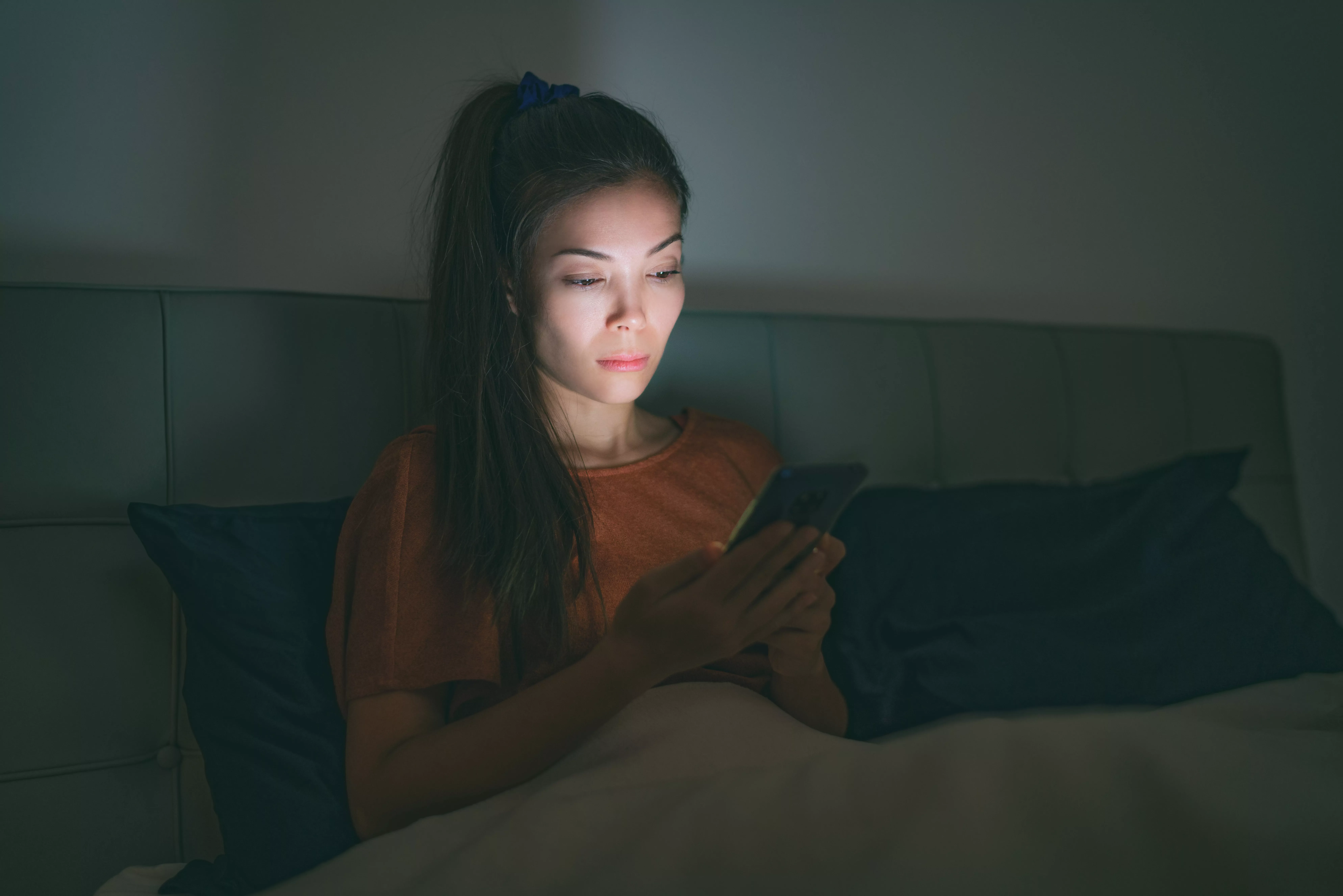 woman using cellphone in bed at night