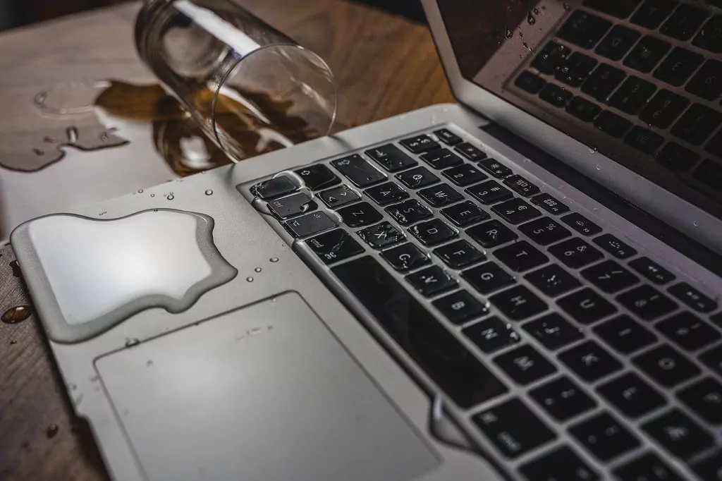Glass of spilled water on laptop