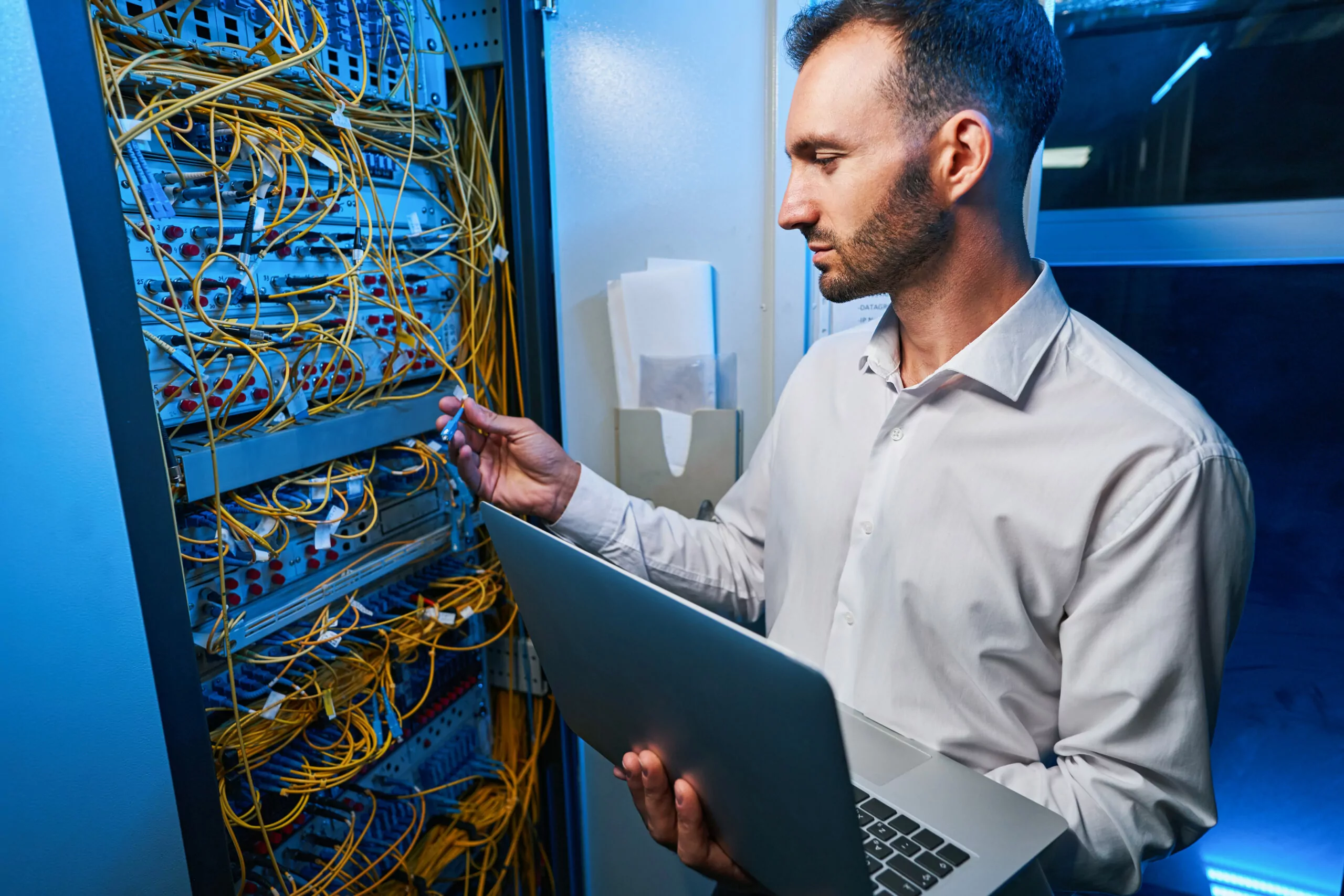 male IT engineer connecting cable to server rack