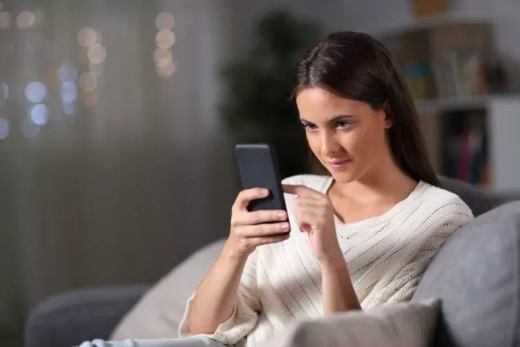 Girl checking mobile phone sitting at home