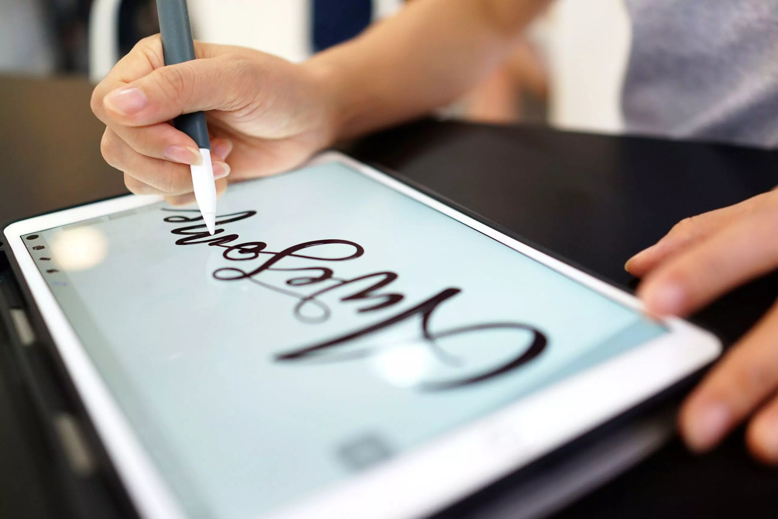 A female using Apple Pencil drawing hand lettering on a iPad usi