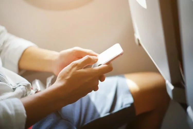 businessman hand holding smartphone during flight