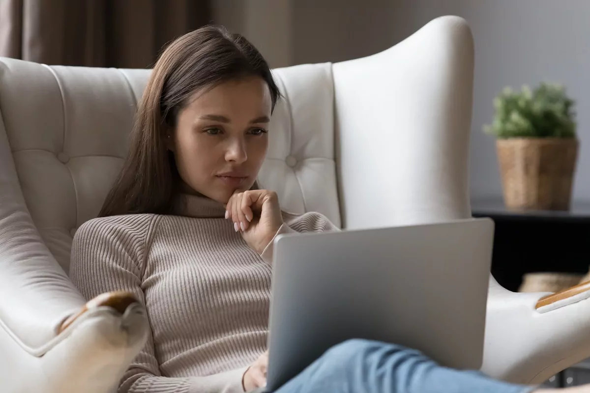 thoughtful young woman using laptop at home