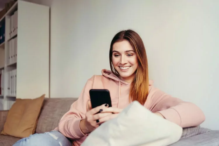 young woman sitting on a sofa and looking at her cell phone
