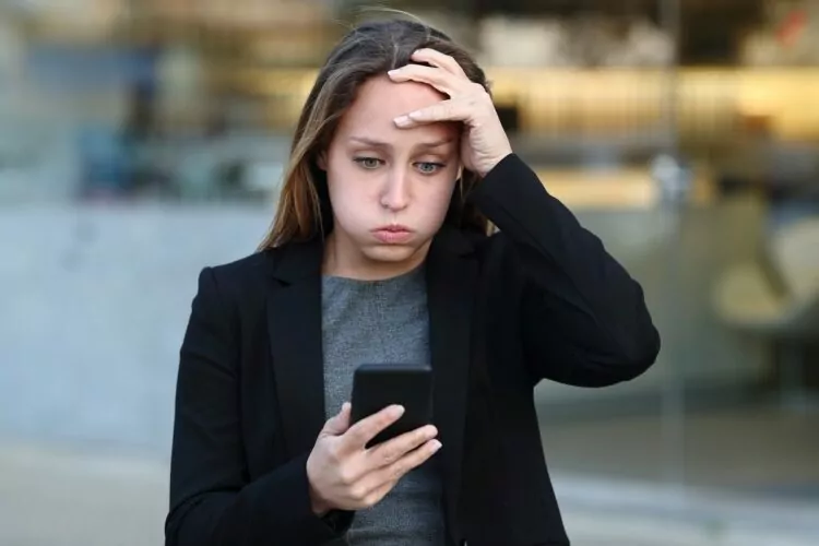 Frustrated businesswoman using cellphone because the number is unavailable or the person she's trying to reach is unavailable.
