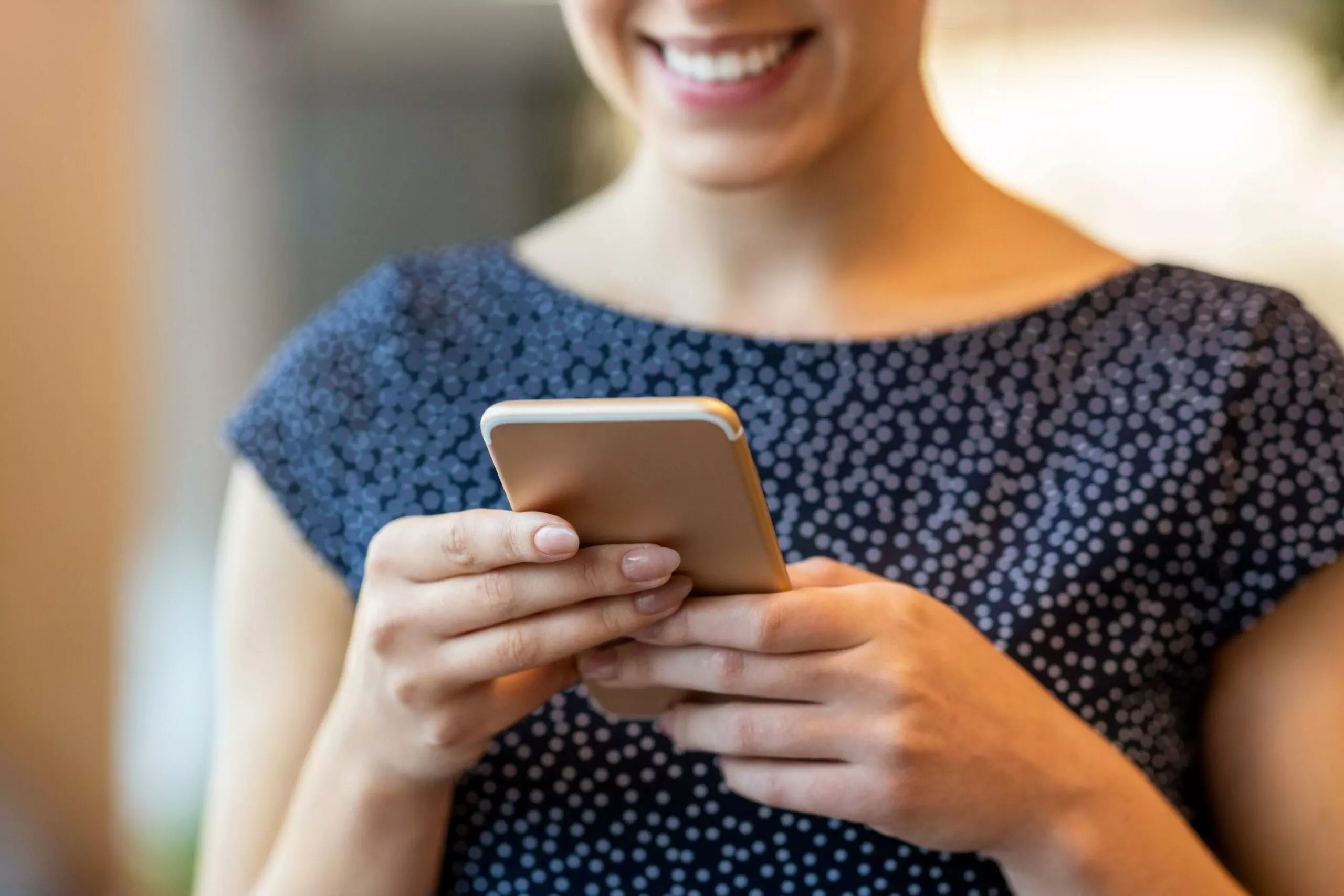 Partial shot of a smiling woman using her smartphone